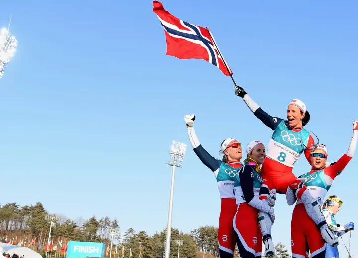 Комmandoen holder en jente med det norske flagget på skuldrene.